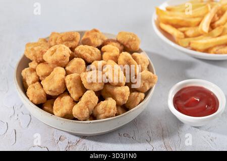 Crispy chicken popcorn with ketchup and French fries on a white background. Fast food. Stock Photo