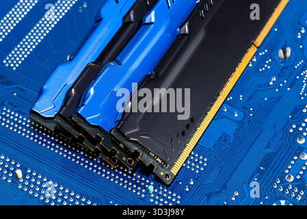 Four DDR memory chips in different colors lying on a blue printed circuit board. Stock Photo