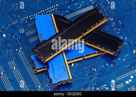Four DDR memory chips in different colors lying on a blue printed circuit board. Stock Photo