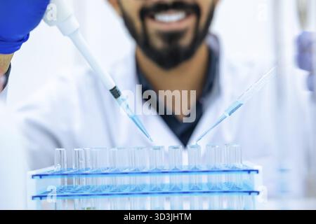 Unrecognizable male scientist using pipette and glass-dropper with flask in medical science laboratory, researching and modern investigation Stock Photo