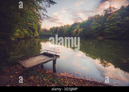 Sunset over the fishing pier. Autumn scene with lake and trees, Autumn Reflection, Bakony Forest and Mountain, Pisztrangos Lake, Hungary. Long exposur Stock Photo