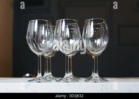 Food, A set of four empty crystal wine glasses displayed on a white marble countertop, reflecting light beautifully Stock Photo