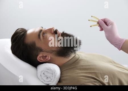 Closeup of bearded man getting beauty injection at aesthetic clinic. Plastic surgeon injecting anti-aging filler in handsome man face. Male cosmetolog Stock Photo