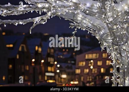 Winter tree with lights and decorations with the defocused city lights of Tromso town in the background, Northern Norway Stock Photo