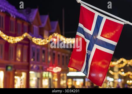Norwegian flag hanging from a pole in Tromso city centre in Christmas period after dusk, Norway Stock Photo