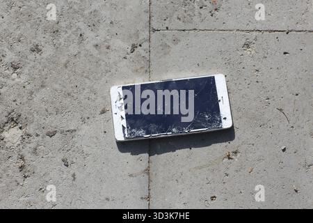 Broken screen mobile phone lies on ground Stock Photo