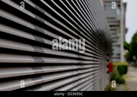 Close perspective of metal louvered facade on Zeeburgerdijk, Amsterdam, Netherlands, with shallow depth of field and receding lines along the street. Stock Photo