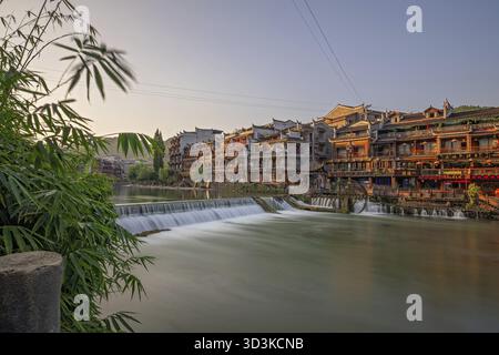 Feng Huang, China - August 2019 : Long time exposure of the small artificial cascade waterfall on the Tuo Jiang riverin the Old Town of Fenghuang know Stock Photo