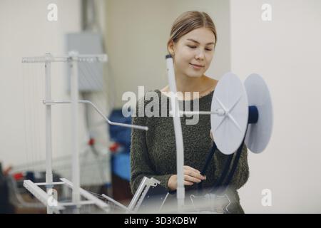 Young beautiful seamstress sews on sewing machine in factory Stock Photo