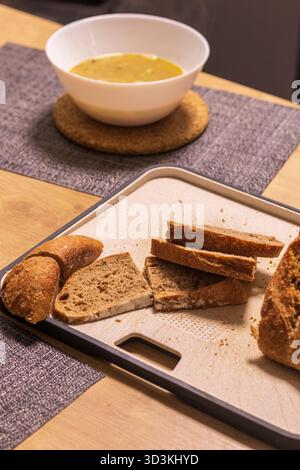Bowl of soup, freshly baked and cut home made bread on the kitchen counter top Stock Photo
