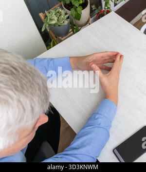 Mid aged man sitting at the table with hands posture in diamond shape Stock Photo