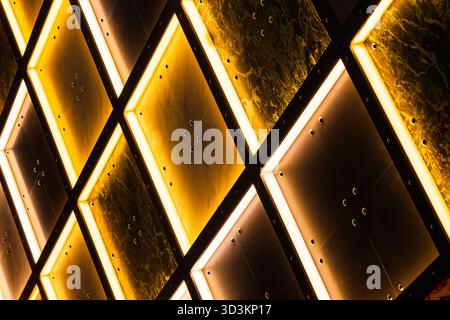 Wall made of decorative tiles with internal illumination in yellow and white with dark areas Stock Photo