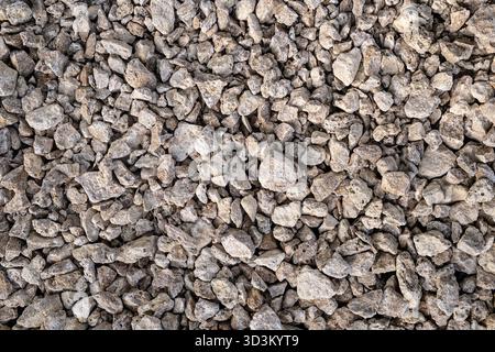 Close-up texture of dry, rough, light gray and beige crushed rock or construction gravel. Stock Photo