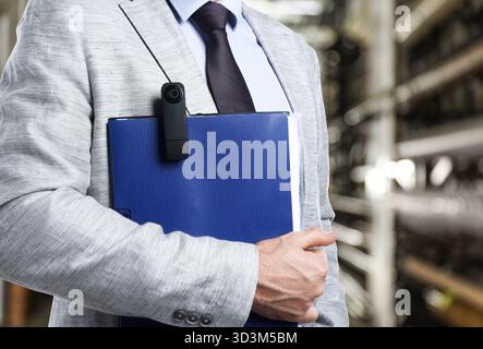 Businessman with hidden spy camera near building indoors, closeup Stock Photo