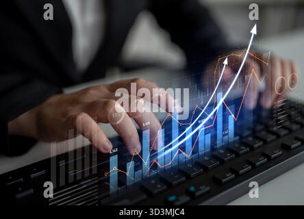 A business professional analyzes financial data while typing on a keyboard. Graphs and charts illustrate growth trends and performance metrics Stock Photo
