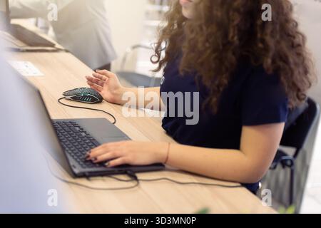 Business woman registering participants on laptop at event reception desk Stock Photo