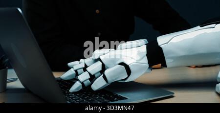 A close-up of a robotic hand interacting with a laptop, showcasing the blend of advanced technology and human-like capabilities in a modern office Stock Photo