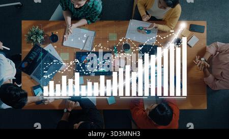 Aerial view of a team engaged in a collaborative meeting, analyzing data trends with graphs and charts displayed on laptops, enhancing productivity Stock Photo