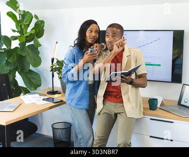 African American coworkers standing in office, analyzing screen graph data with laptops and tablet Stock Photo