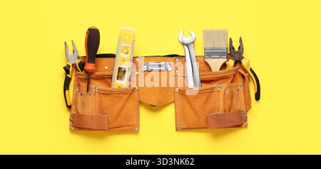 Belt with different construction tools on yellow background, top view Stock Photo