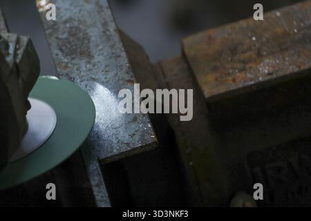 Close up of craftsman at work, using grinding machine with diamond cutter for precise stone processing in an industrial workshop. focus is on marble d Stock Photo