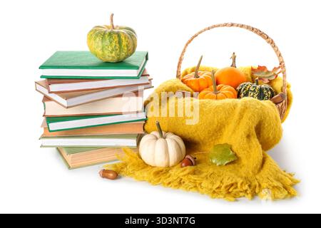 Stack of different books, basket with scarf and pumpkins on white background Stock Photo