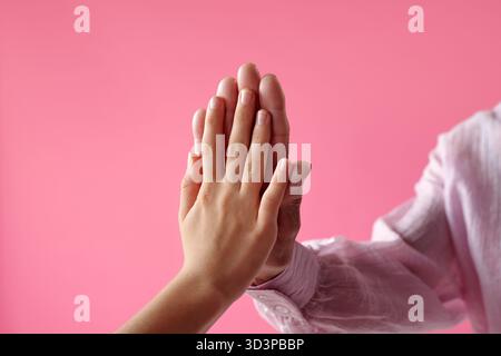 Caucasian Young Woman and Senior Man Touching Hands Against Pink Background Stock Photo
