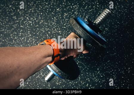 Unrecognisable man working out with a dumbbell at the gym. Stock Photo