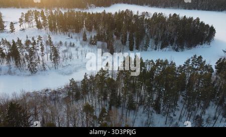 Aerial view of winter forest and frozen river at sunset Stock Photo