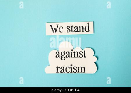Blue background with a white cloud and the words We stand against racism written on it Stock Photo