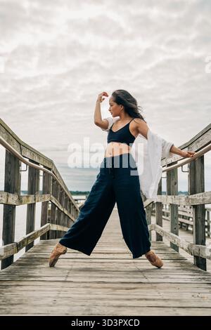 Ballerina dancing outdoors on wooden pier at daytime Stock Photo