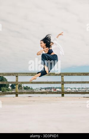 Female dancer performing dynamic jump on pier Stock Photo