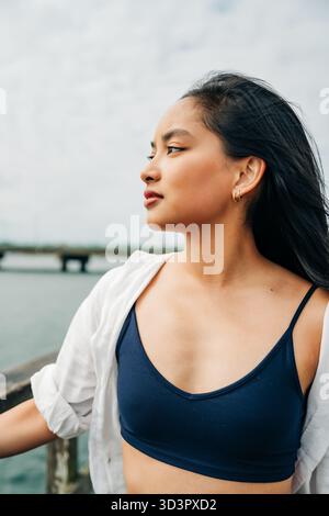 Young asian woman contemplating ocean view from pier Stock Photo