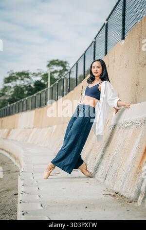 Ballerina posing in pointe shoes on urban concrete wall Stock Photo