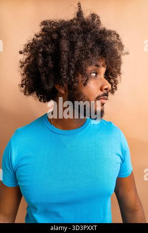 Young man with curly hair looking sideways thoughtfully Stock Photo