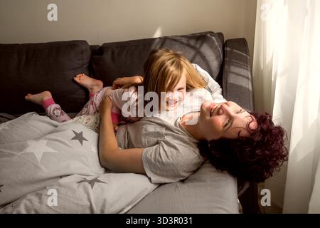 Two sisters playing together in bed in the morning Stock Photo