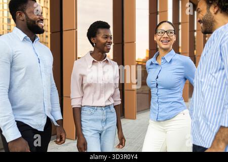 A diverse group of business professionals engage in a lively conversation on a city street. They display a sense of teamwork and camaraderie, clad in Stock Photo