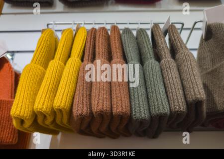 Rows of folded, colorful woolen knitwear including socks and scarves neatly displayed on white shelves in a retail store. Ideal for autumn and winter Stock Photo