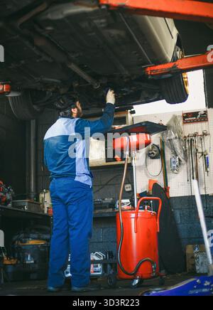 A mechanic is working on a car lifted in an auto repair shop Stock Photo