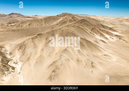 An aerial view captures the vast expanse of the Dunas de Saujil in Catamarca, Argentina. The undulating sand dunes stretch beneath a clear blue sky, c Stock Photo