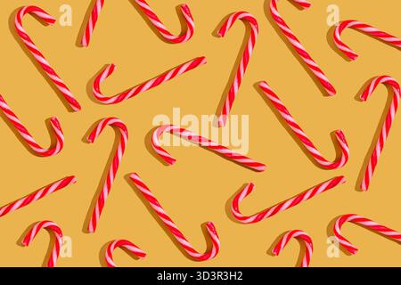 A festive pattern of red and white candy canes arranged on a bright yellow background, symbolizing the holiday season with a joyful and sweet touch. Stock Photo