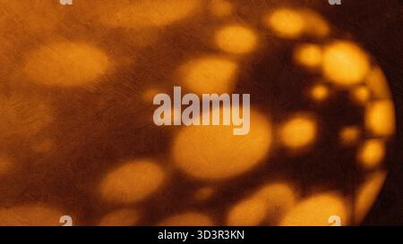 Warm light creates abstract patterns on a wall, casting shadows that form various shapes. The scene captures an artistic effect in a calm setting. Stock Photo