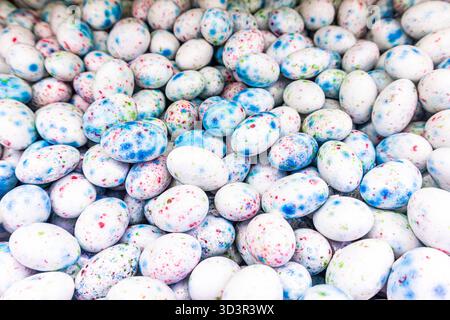A vibrant close-up image of colorful speckled candy eggs with blue, red, and green spots. The candies are piled together, creating an eye-catching and Stock Photo