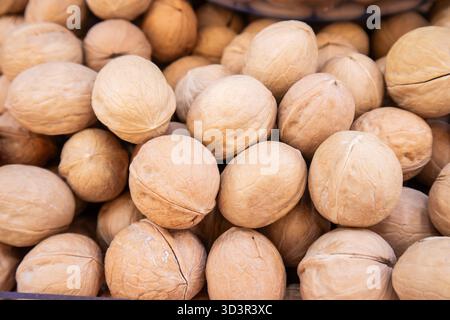 A close-up image showcasing a pile of brown whole walnuts in their natural shells. Perfect for illustrating the concept of natural, raw, and nutritiou Stock Photo