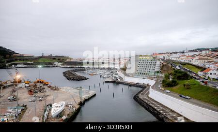 A scenic view of the Port of Angra do Heroismo from the historic Fort of Sao Sebastiao, showcasing the marina and coastal landscape of Terceira Island Stock Photo