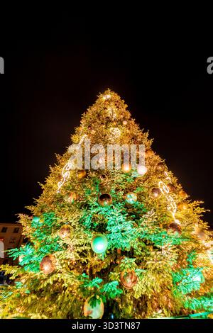 A Christmas tree decorated with various tree decorations on a black sky background, very colorful Stock Photo