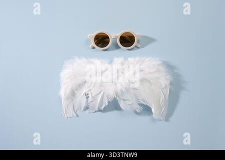 Composition with soft white feathers and brown walnuts on blue background. Stock Photo