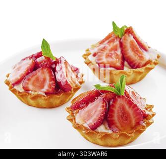 Food, Tartlets with custard, strawberries and mint served on white plate Stock Photo