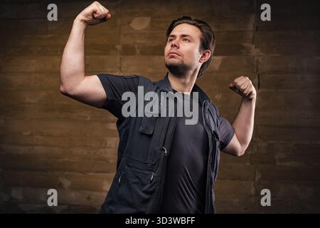 Young strong handsome man posing on wall background Stock Photo