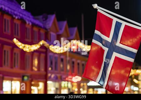 Norwegian flag hanging from a pole in Tromso city centre in Christmas period after dusk, Norway Stock Photo